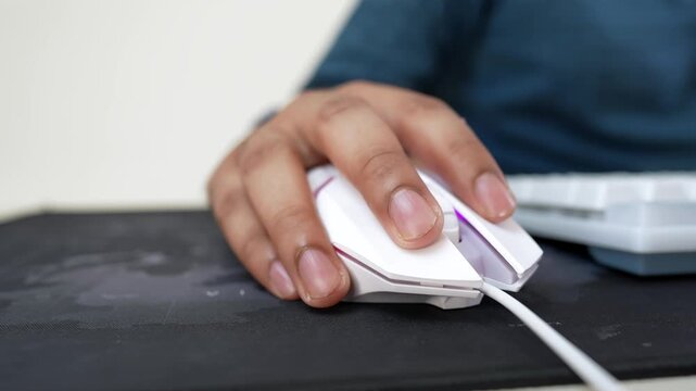 Close-up of a hand using a white computer mouse on a black mouse pad