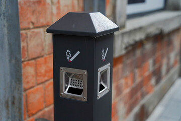 Modern street ashtray with built in hole in metal post, conditions for smokers, not to litter with cigarette butts public place. Outdoor smoking area zone