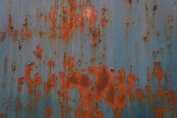 The wall is covered in peeling paint and has a rough texture. The grey color of the wall is faded...