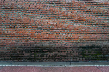 Red brick wall with moss and fungus growing around the surface of the red brick wall, street wall background