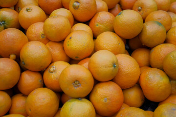 Pile of oranges on sale at farmer's market, supermarket or grocery shop. Background photo of ripe organic, vegan or vegetarian raw food. Sweet fruits.