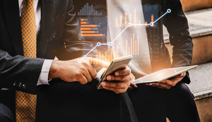 Two business professionals examine data on mobile devices with growth graphics, highlighting...