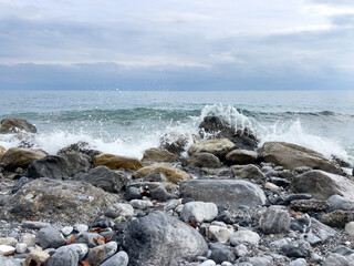 Rocky shoreline with waves crashing under cloudy sky