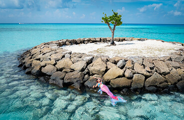 Young woman  relaxation with mermaid tail  on the rock  beach