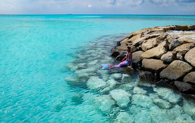 Young woman  relaxation with mermaid tail  on the rock  beach