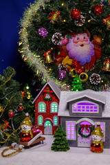 Beautiful houses with green and purple lights in the windows between snowmen under a Christmas wreath