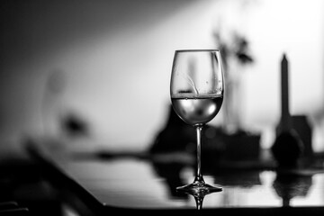 Shallow depth of field (selective focus) details with a glass of white wine on a table in a dark room with back light