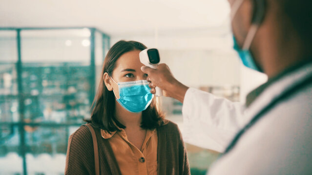 Thermometer, doctor and patient with mask in office, examine symptoms and temperature for diagnosis. Medical exam, health assessment and people with vital signs check, physician consultation and care