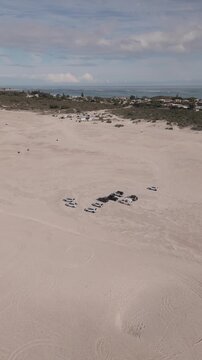 Vertical aerial footage of Lancelin Sand Dunes in Perth, Western Australia. The footage pans towards a cluster of four-wheel drive vehicles.