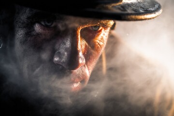 Intense gritty portrait of determined worker in dark hat facing challenges resilient focused industrial smoky environment strong emotion courage determination hard work labor dedication