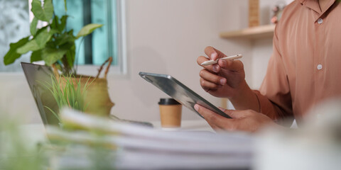 Remote Work. Professional using tablet and stylus for digital note-taking in a cozy office.