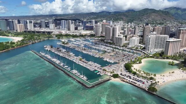 Aerial drone footage of Ala Wai Boat Harbor in Honolulu, Oahu, Hawaii, showing boats, tropical waters, palm trees, and the scenic Waikiki coastline with hotels and city skyline in the background.