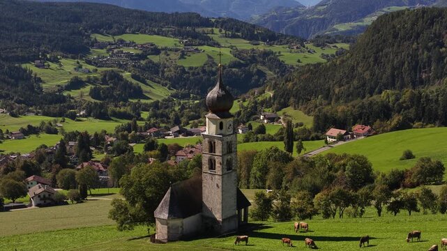 Small church, chiesa in the Italian dolomites. Alpine fields, agricultural grass lands. Aerial video.