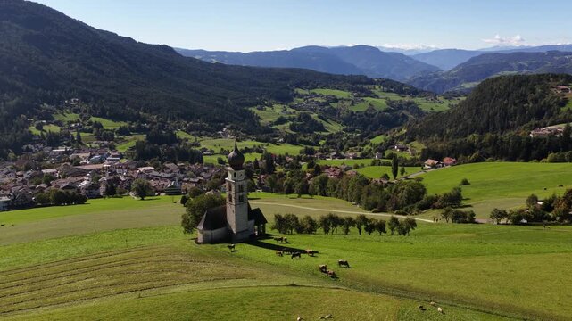 Small church, chiesa in the Italian dolomites. Alpine fields, agricultural grass lands. Aerial video.