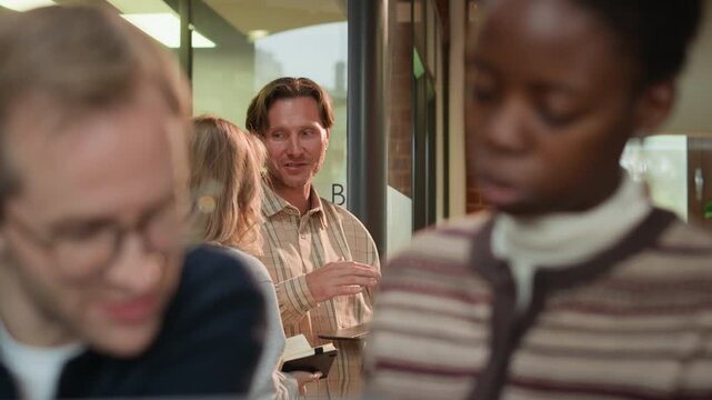 Selective focus shot of diverse business team coworking in modern office, discussing ideas and project details in pairs
