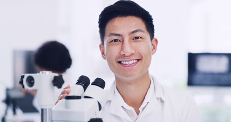 Portrait, scientist and Asian man in laboratory with microscope, medical research and development. Smile, science and face of person with microbiology equipment, professional and career pride