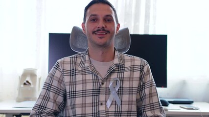 Close-up of man smiling while holding and pinning blue ribbon symbolizing support for Movember, prostate cancer, and men’s mental health awareness.