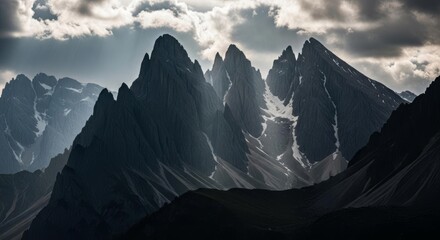 Dramatic Mountain Peaks Under Cloudy Sky with Light Rays