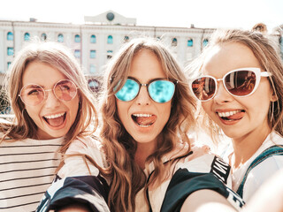 Portrait of three young beautiful smiling hipster in trendy summer clothes. Sexy carefree women...