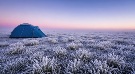 A blue tent in a frosty field at dawn under a colorful sky
