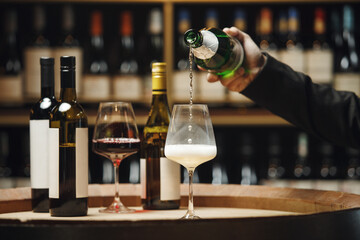 Unrecognizable Professional Sommelier Pouring Sparkling Wine in Wine Cellar