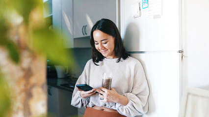 Woman, phone and smile in kitchen with smoothie, drink and glass for gut health with web chat in home. Person, smartphone and happy with mobile app, contact or social network with nutrition in house