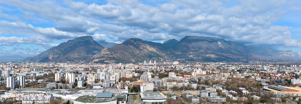 Urban skyline with mountain backdrop under dramatic clouds
