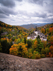 Naklejka premium Autumn view of Špania Dolina village with the Church of Transfiguration surrounded by colorful forest and mining hills in Slovakia.