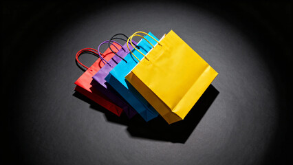 Colorful shopping bags arranged in a row on a dark surface under focused lighting