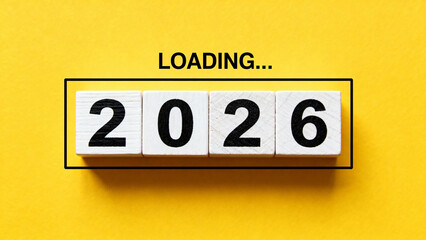 Wooden blocks displaying '2026' with 'LOADING...' text above on a yellow background