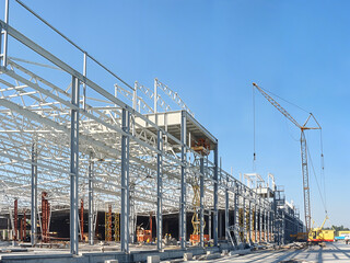 Construction site with crane and steel framework against a clear blue sky