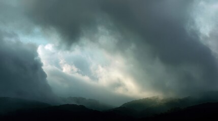 Landscape photograph of a mountain range. the sky is filled with dark, ominous clouds that are covering most of the sky. the clouds are thick and billowing, creating a dramatic and ominous atmosphere.