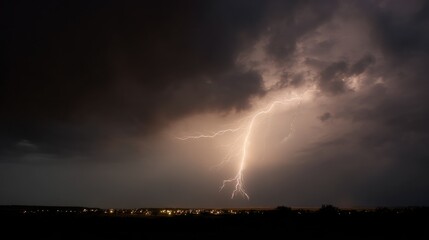 Photograph of a lightning bolt striking over a city at night. the sky is filled with dark, ominous clouds and the lightning bolt is bright and striking in the center of the image.