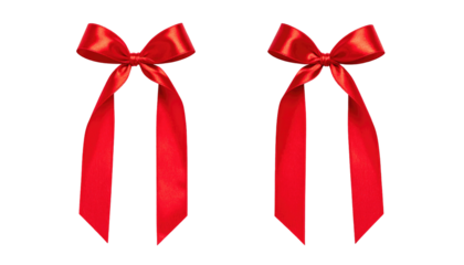 Two vibrant red satin bows with dangling ribbons isolated on a dark backdrop create a festive holiday theme