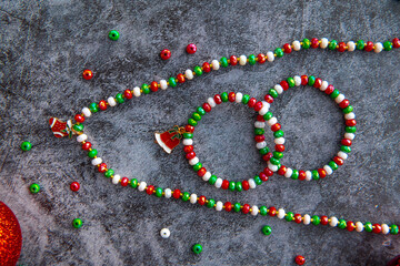 Christmas themed handmade necklace and bracelets on a stone background surrounded by Christmas balls.