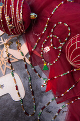 Christmas themed handmade pendant necklaces and bracelets on gray background surrounded by Christmas balls and nutcracker.