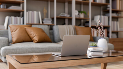 Laptop and vase on glass top wooden table and sofa couch aside bookshelf in living room of modern house. Product Display, 3D Rendering,3D Illustration.