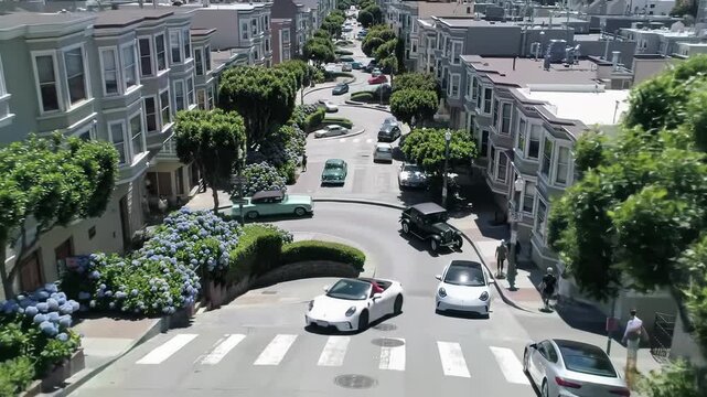 aerial time-lapse video of lombard street, san francisco, as diverse cars navigate its winding curves bordered by lush foliage, hydrangeas, and charming houses. iconic urban landmark