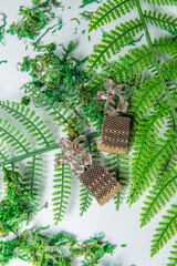 Handmade earrings set with golden beads on a blue background with green leaves.