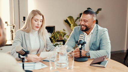 Podcast, people and talk with paperwork in studio, business show and reading economy review. Document, happy podcaster and recording audio with mic, panel and live stream for entrepreneur advice