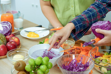 Hands of asian senior mother and adult daughter preparing healthy vegetable salad cutting cabbage carrots together in kitchen showing teamwork love freshness and family bonding lifestyle at home