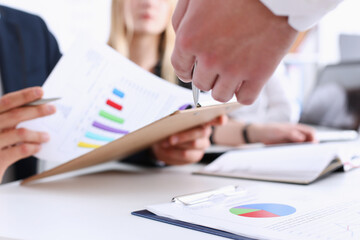 Group of people deliberate on problem with clipboard pad closeup. White collar check money papers, stock exchange market, earnings list, partnership agreement discussion concept
