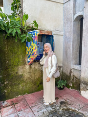 Woman in a light outfit smiles while using a vintage phone in a lush, vibrant setting