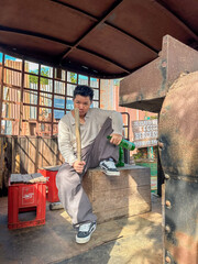 A young man relaxes on a crate with a stick in a sunny spot adorned with vintage decor