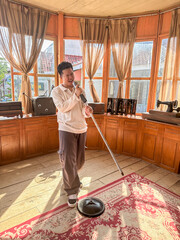 A young man stands confidently with a microphone, entertaining in a warm, sunlit room