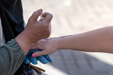 Hand decorated with henna in a market stall in Marrakech, Morocco during a sunny day