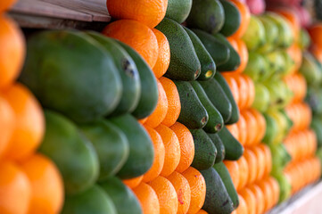 Fresh oranges and avocados stacked neatly in a colorful market in Marrakech, Morocco.