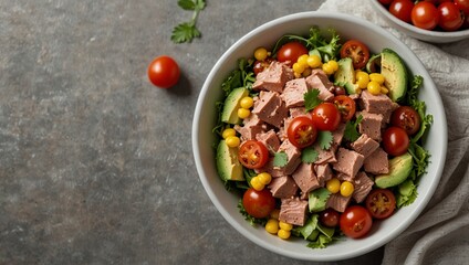 Fresh salad bowl with diced luncheon meat cherry tomatoes sliced avocado sweet corn and mixed greens on a gray surface