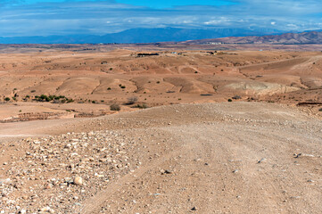 Expansive view of Agafay desert with rugged terrain and distant mountains under blue sky