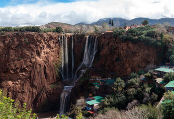 Ouzoud waterfalls cascade through cliffs, framed by lush greenery and blue skies.